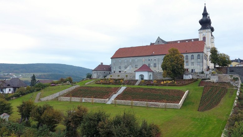 Landschaft mit Kirche und Gartenanlage auf einem Hügel.