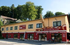 Außenansicht einer Bäckerei mit gelber Fassade und rotem Schild.