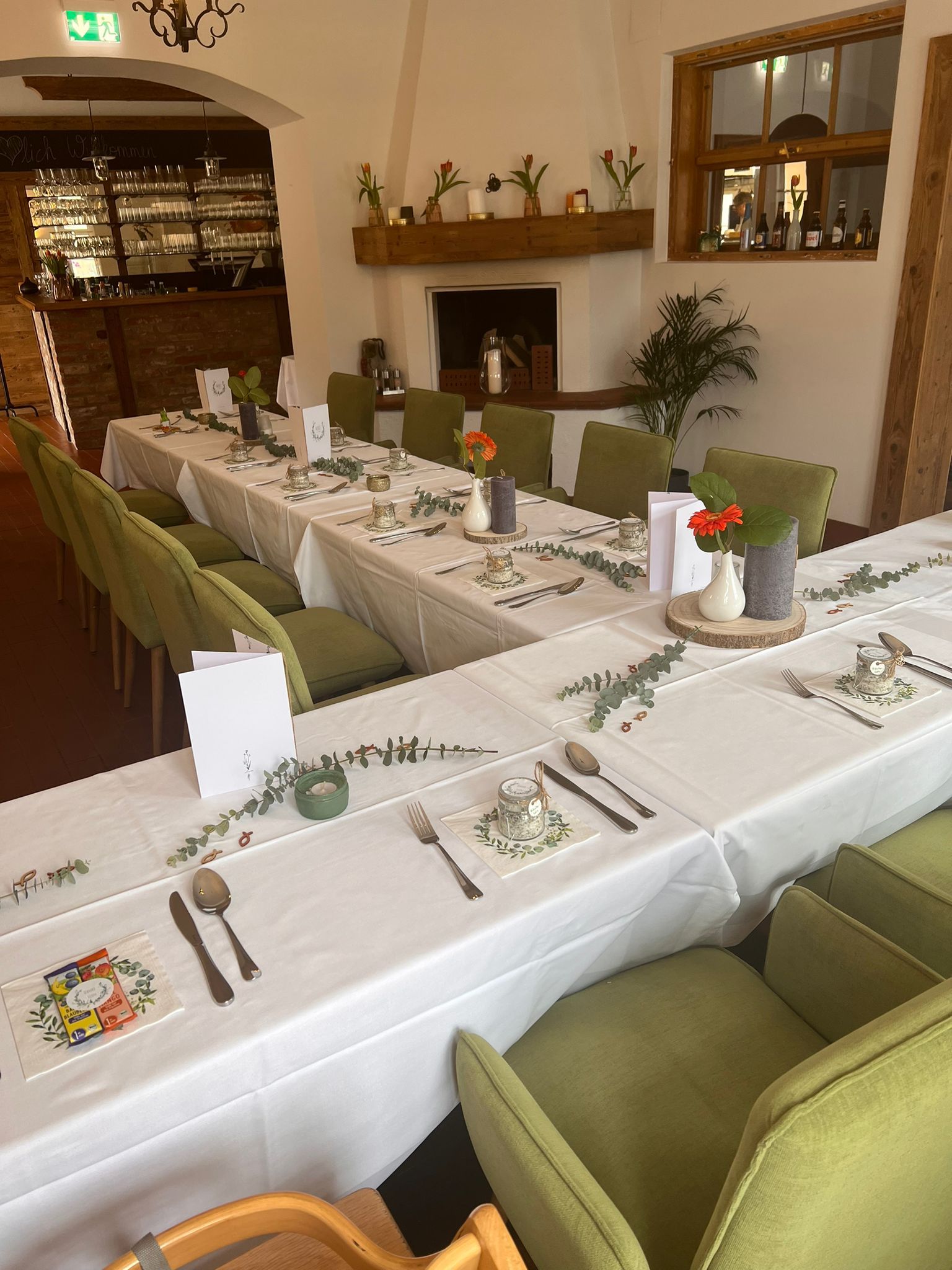 Elegantes Restaurant mit gedecktem Tisch, grünen Stühlen und Kamin.