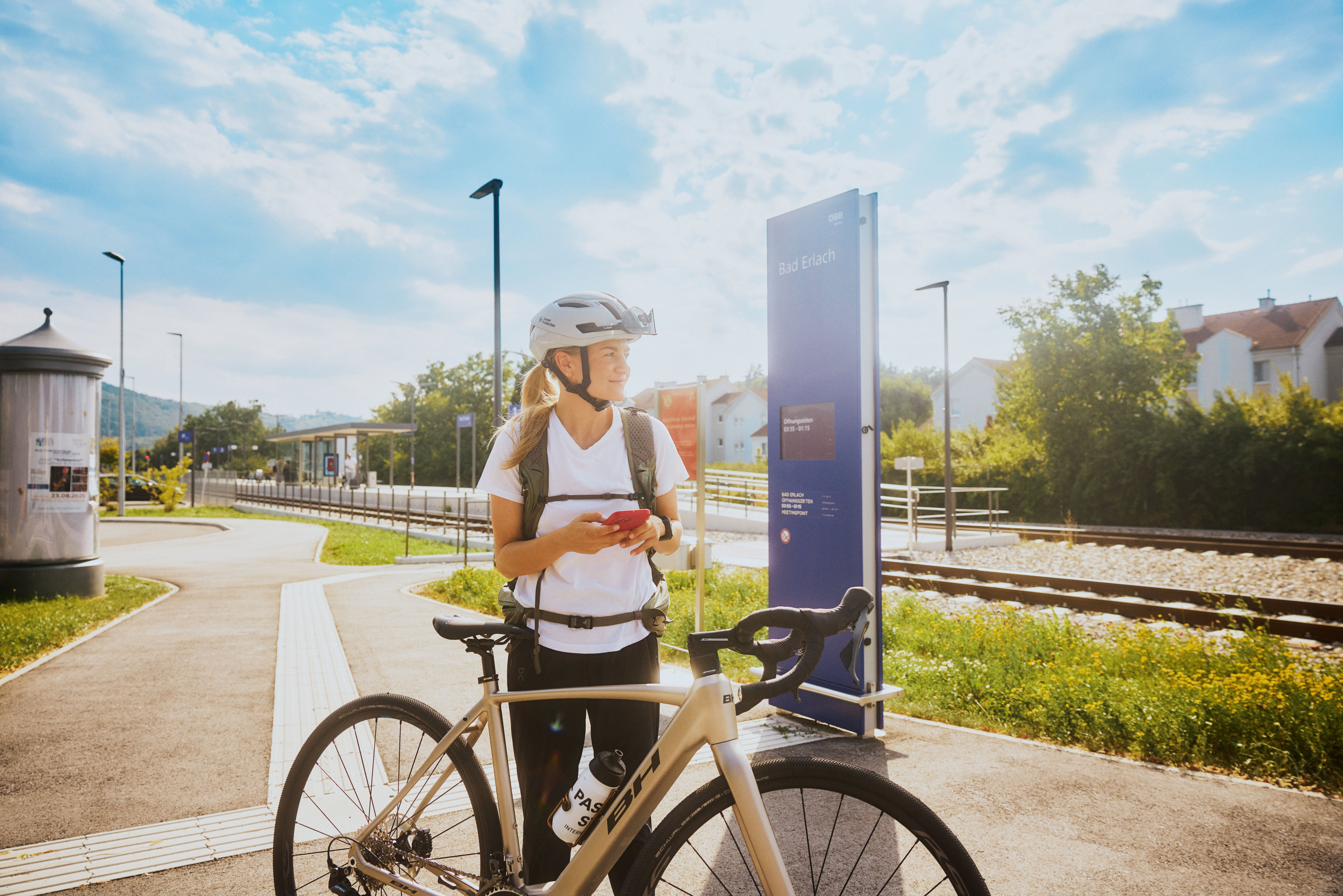 Eine Frau mit Fahrradhelm steht neben einem Fahrrad am Bahnhof in Bad Erlach.