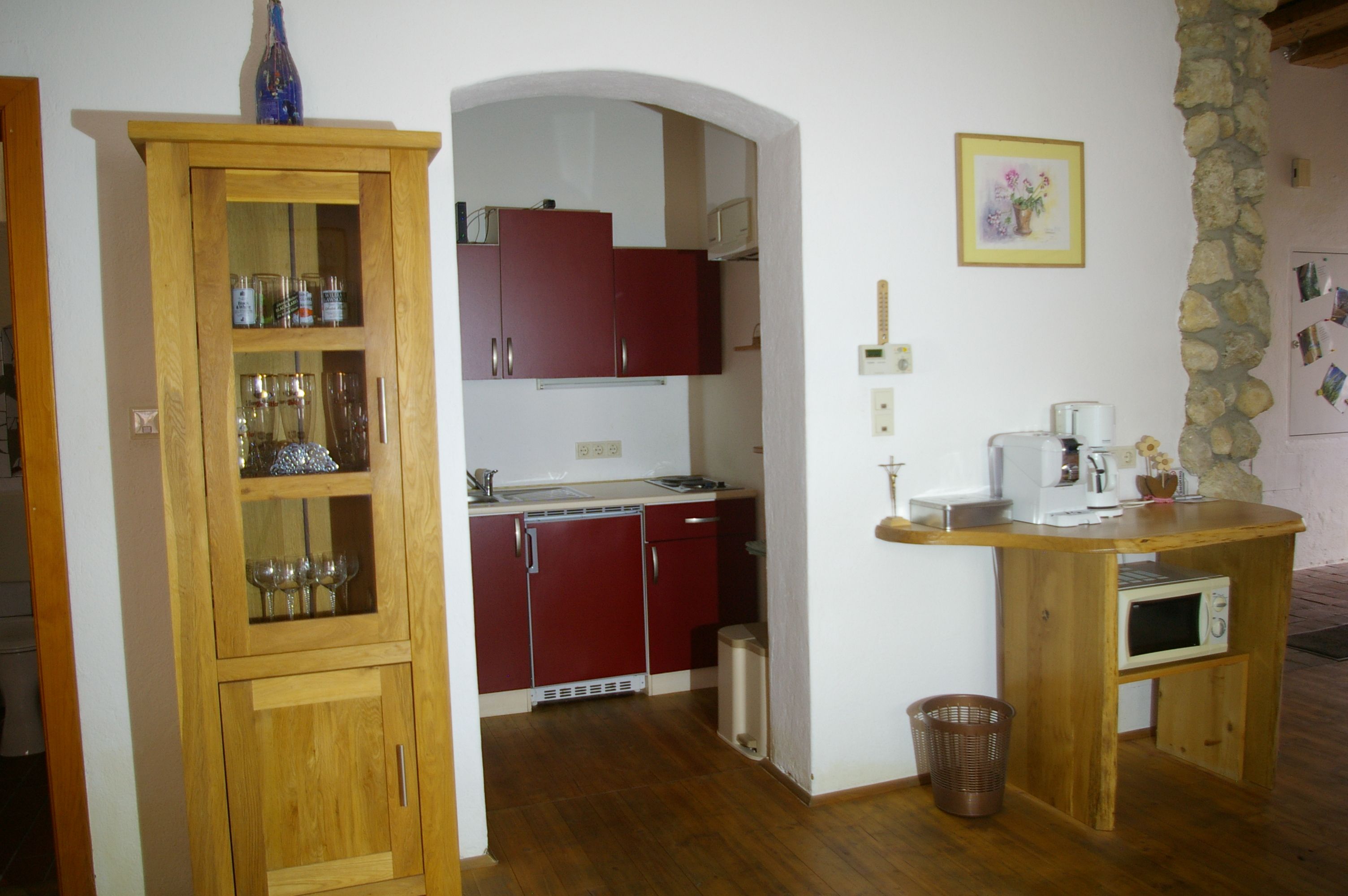 Kleine Küche mit Holzmöbeln, roten Schränken und Kaffeemaschine.