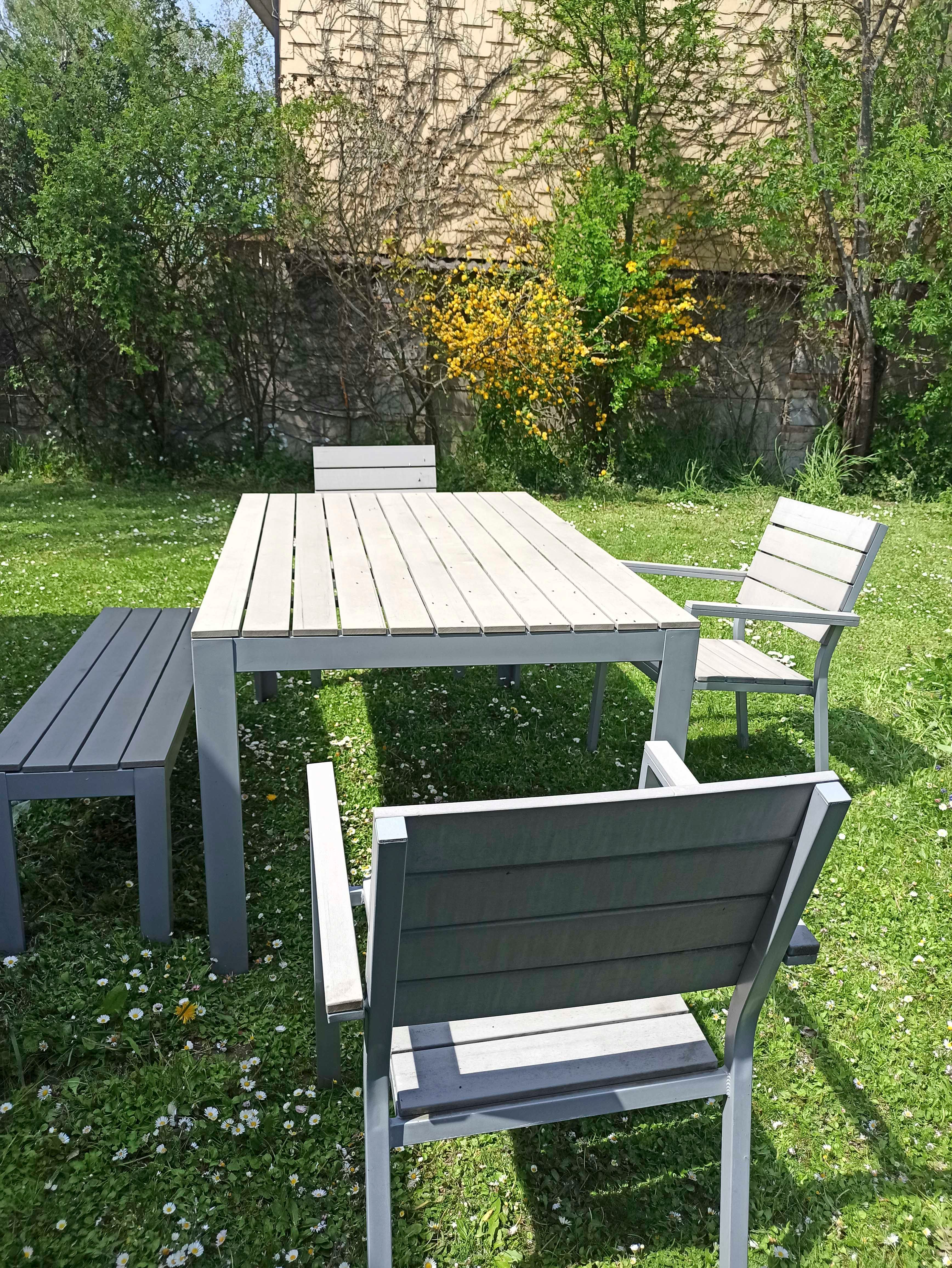 Gartenmöbel-Set mit Tisch, Stühlen und Bank auf einer Wiese.