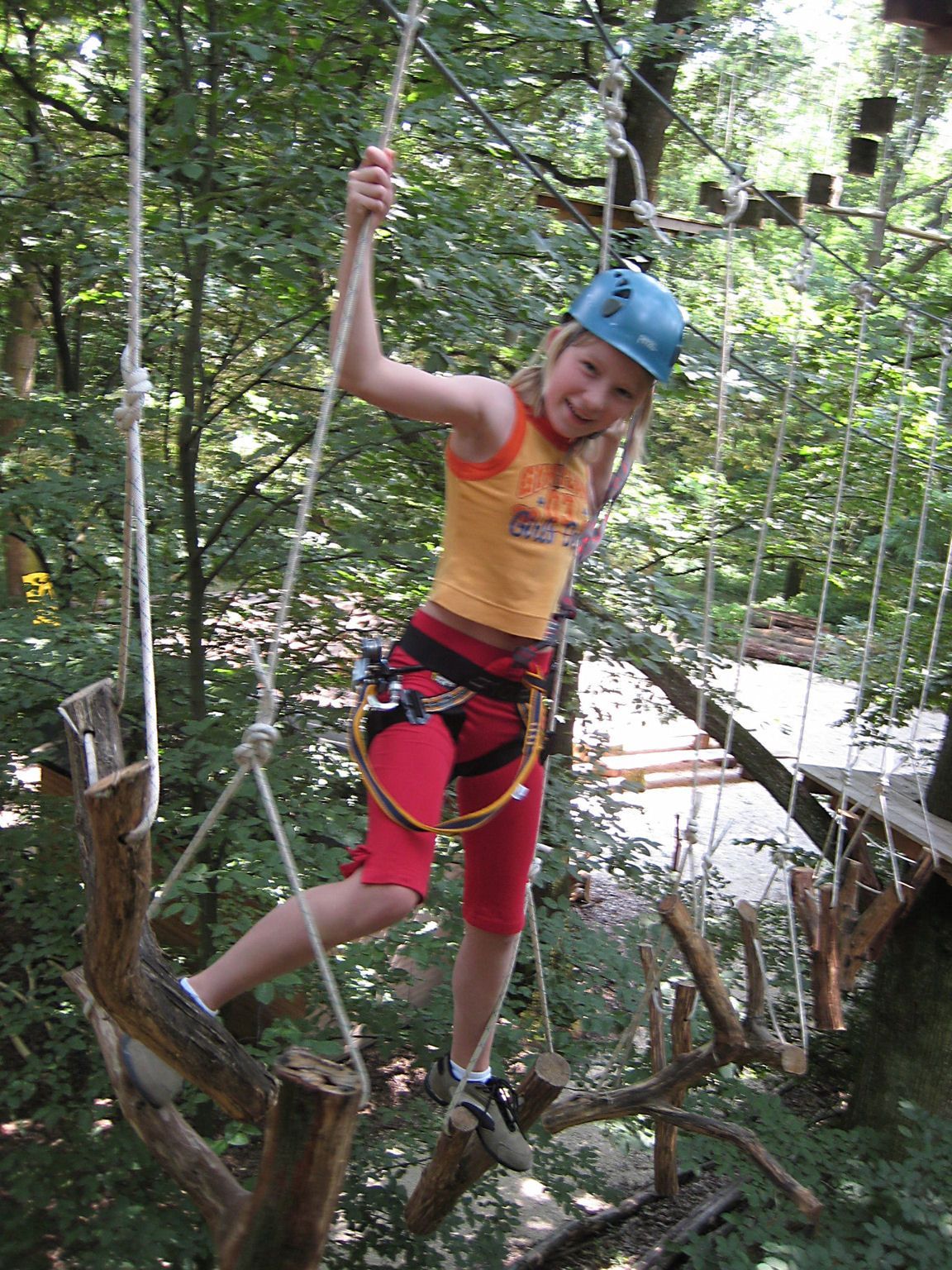 Kind mit Helm im Kletterpark auf einem Seilparcours.