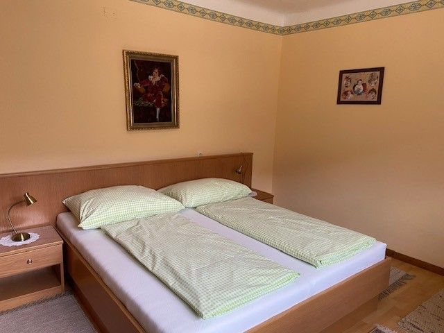 Ein gemütliches Doppelzimmer mit einem Doppelbett, grüner Bettwäsche und zwei Bildern an der Wand.