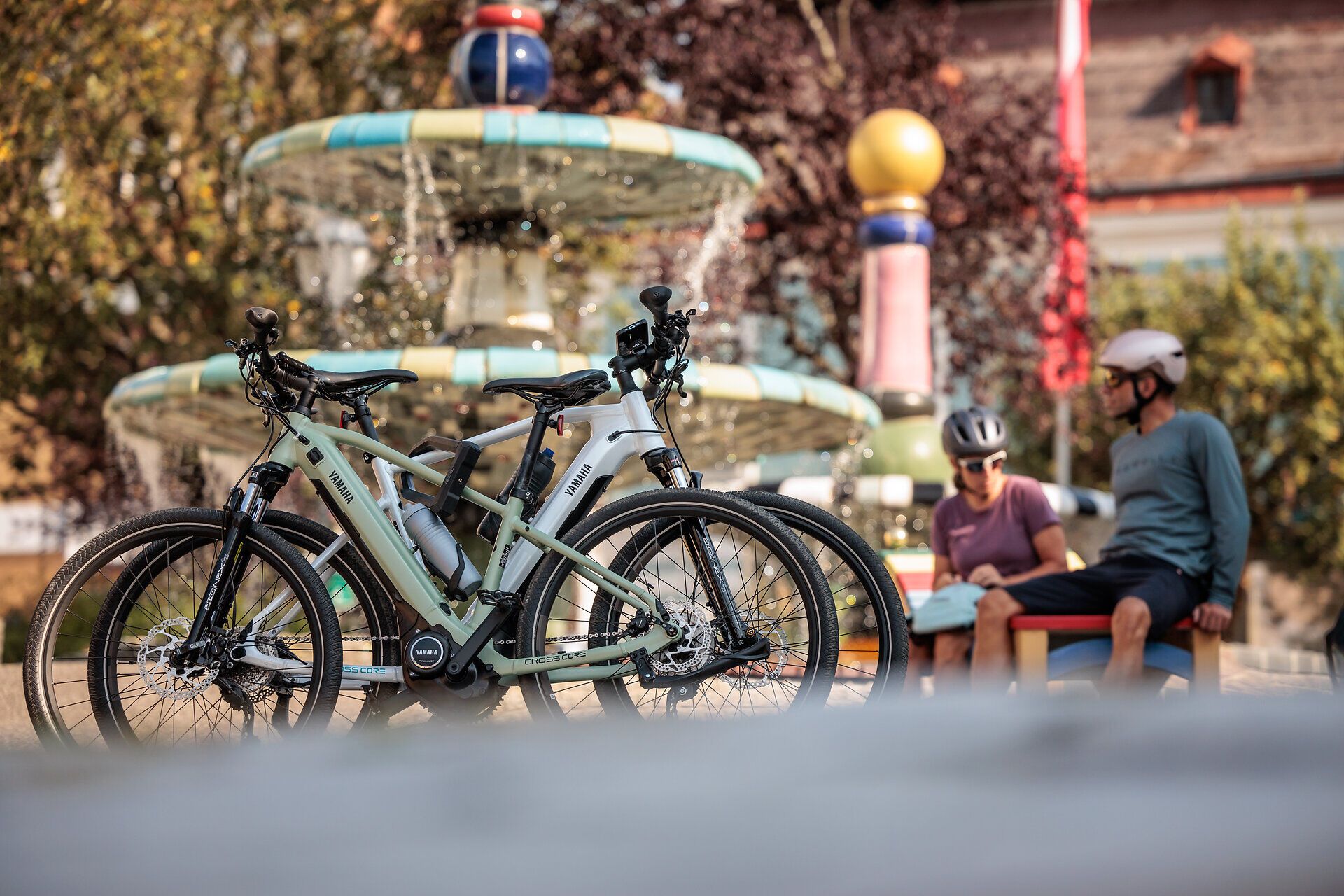 In der warmen Sonne entspannen Radfahrer am Hundertwasserbrunnen, umgeben von sprudelndem Wasser und bunten Pflanzen. Die frische Luft und die malerische Kulisse laden dazu ein, die Schönheit der Natur zu genießen und neue Energie zu tanken.