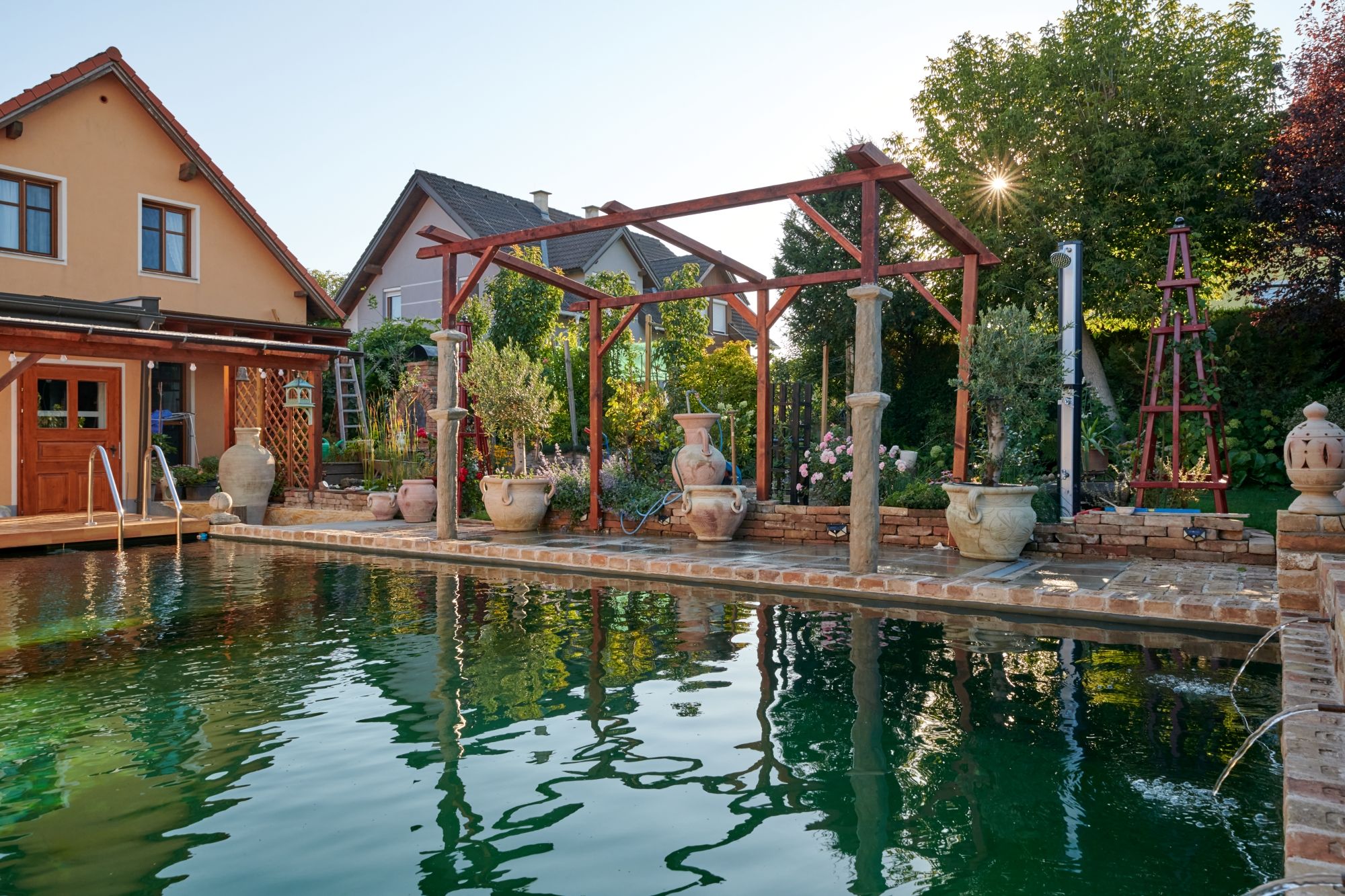 Ein mediterraner Garten mit Pool, Terrakotta-Töpfen und Holzkonstruktionen im Weinviertel.