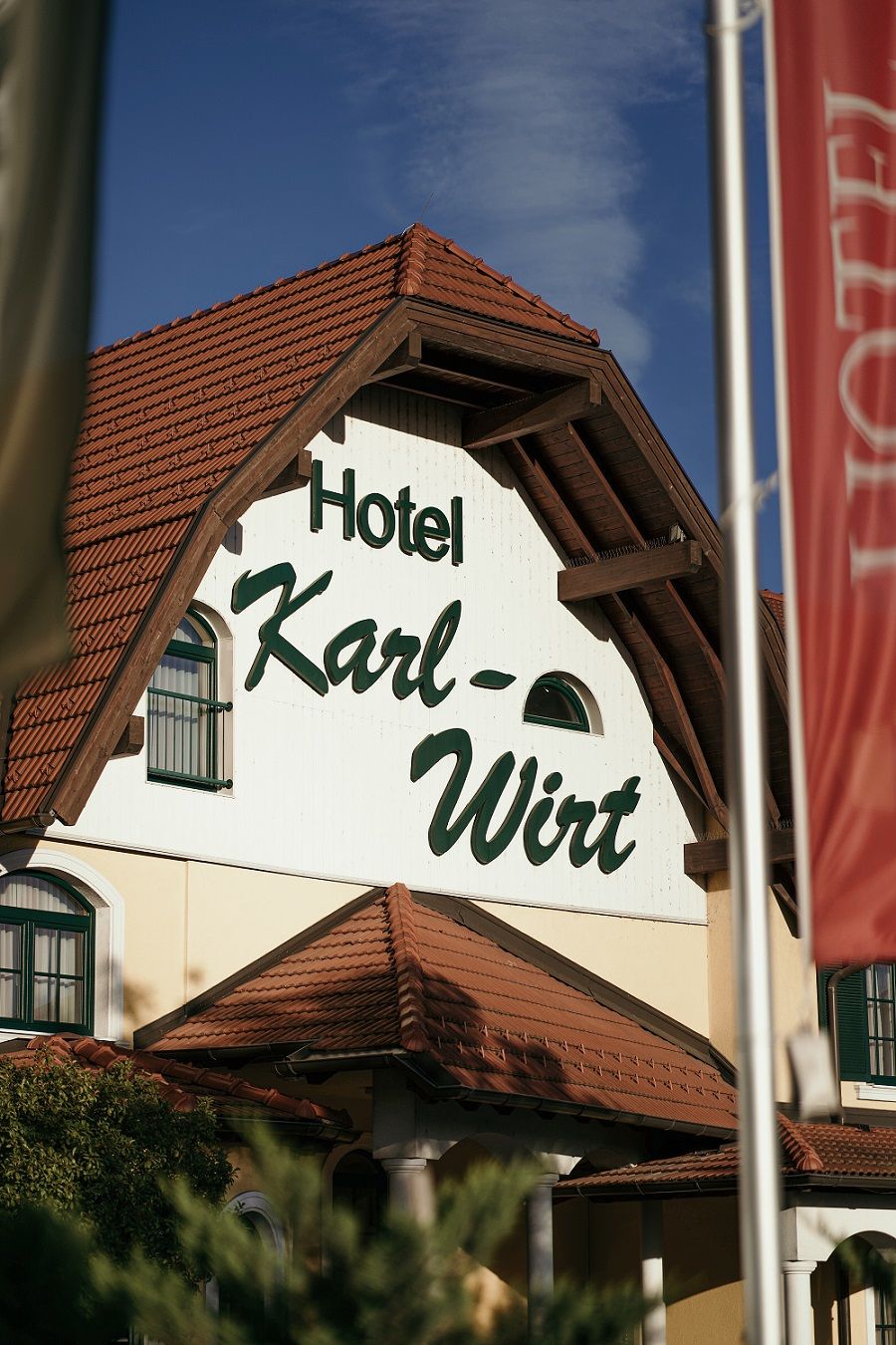 Fassade des Hotels Karl-Wirt mit rotem Dach und grünen Fensterläden.