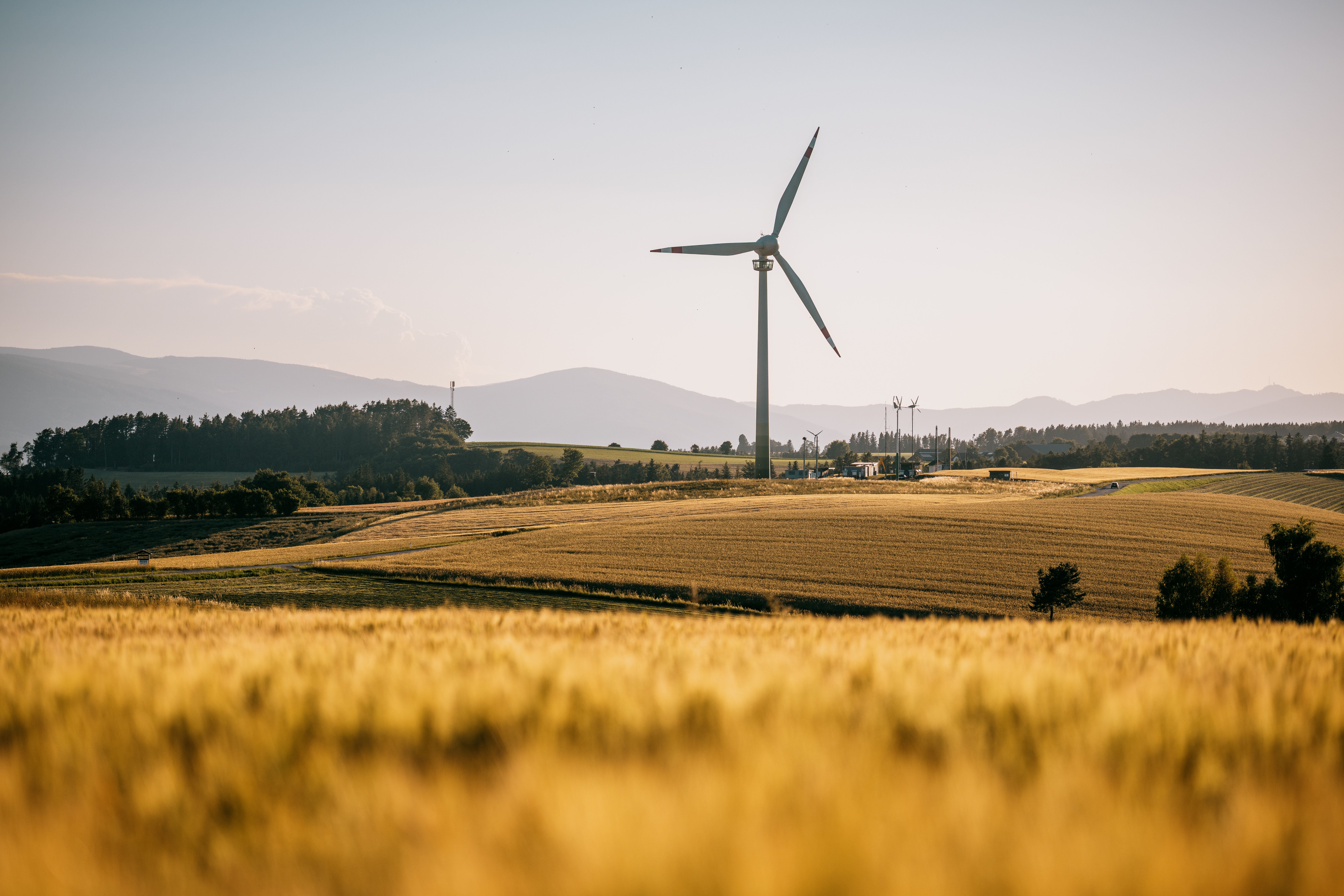 Das Windrad Lichtenegg auf einem Feld, im Hintergrund Berge