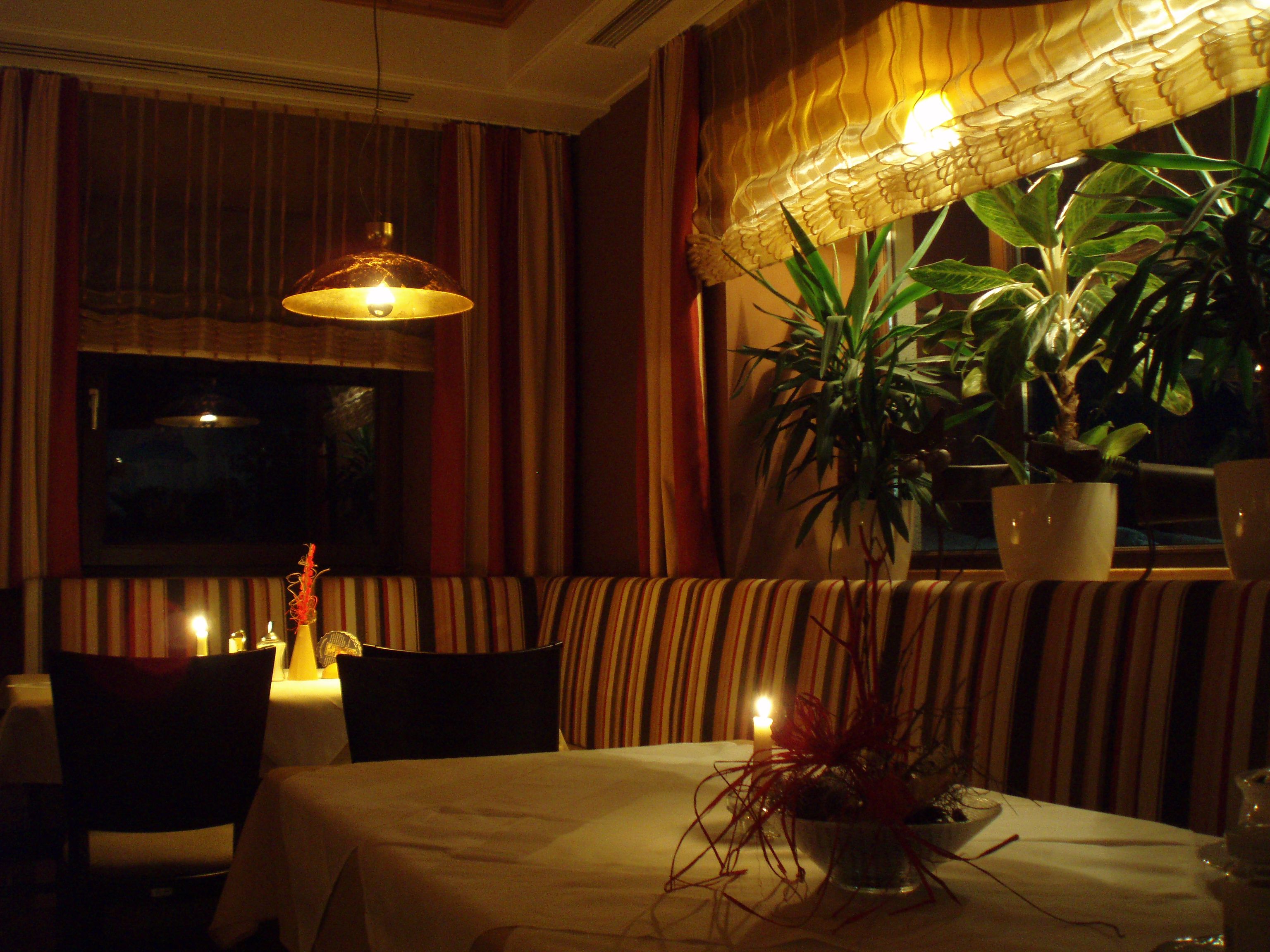 Gemütliches Restaurant mit Kerzenlicht und Pflanzen.