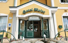 Eingang des Hotel Moser mit gelber Fassade und grünen Türen.