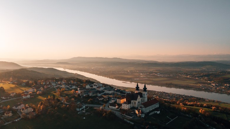Luftaufnahme einer Kirche bei Sonnenuntergang, umgeben von Fluss und Landschaft.