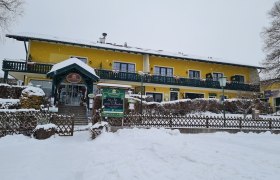 Gelbes Gebäude im Schnee mit grüner Veranda und Eingang.