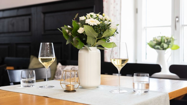 Tisch mit zwei Weingläsern, Vase und Kerze