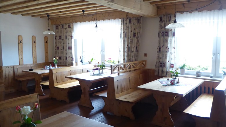 Gem&uuml;tliches Gastzimmer mit Holzm&ouml;beln und Blumen auf den Tischen.