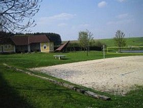 Freizeitanlage mit Volleyballfeld, Wiese und Gebäuden.