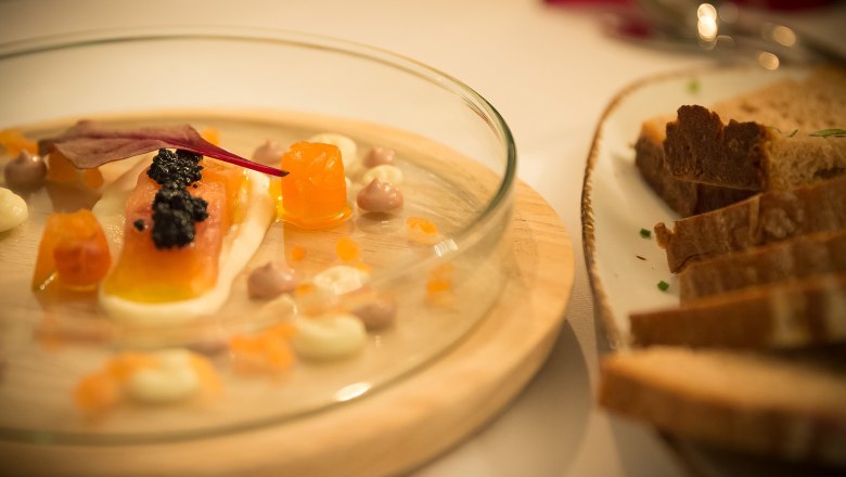 Hausgebeizte Lachsforelle mit Kaviar und Brot auf einem Teller.