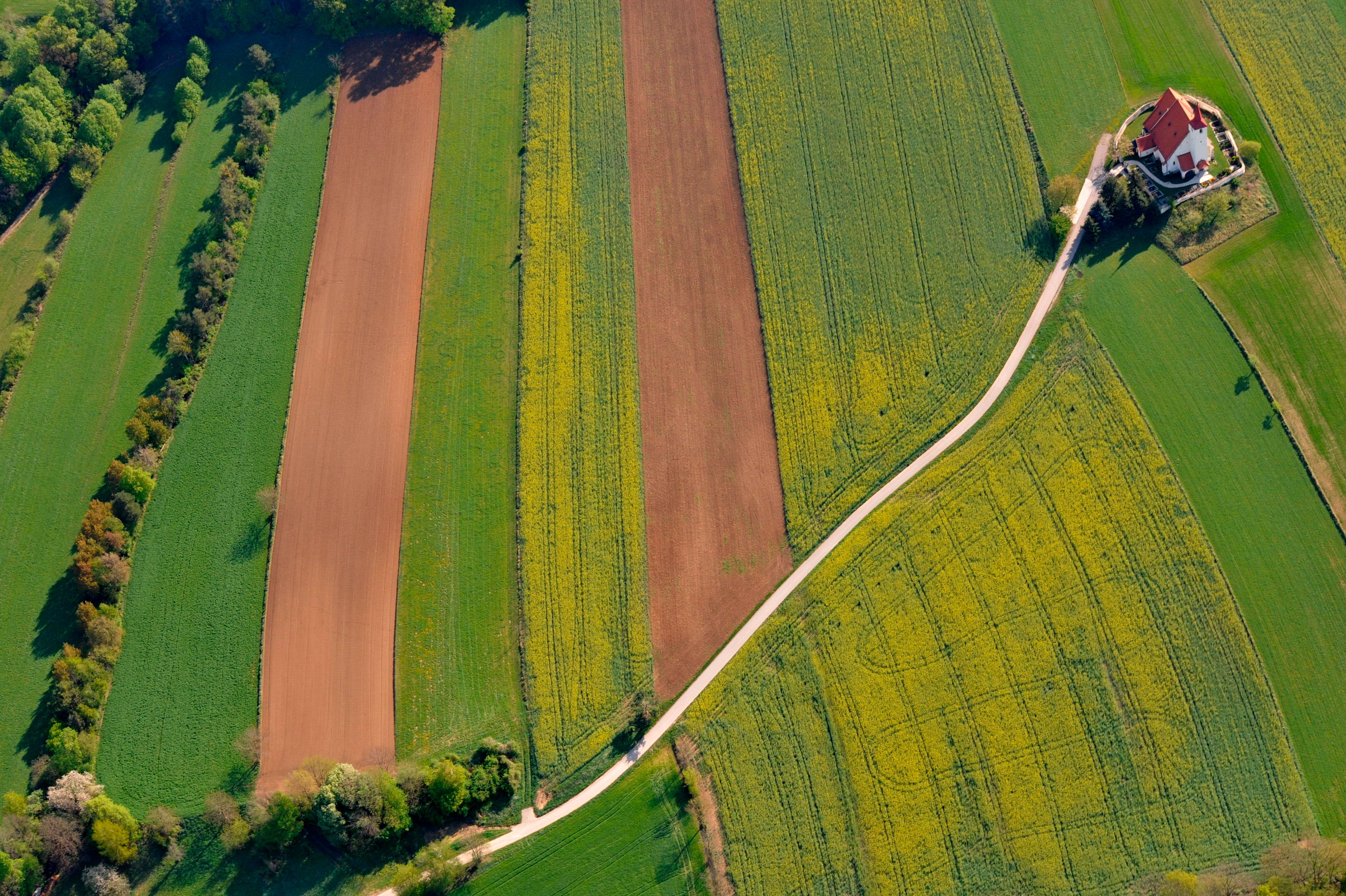 Luftaufnahme von Feldern mit einer Kirche am Rand.