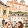 Zwei Frauen genießen Eisbecher im Gastgarten mit Blick auf das Stift Melk.