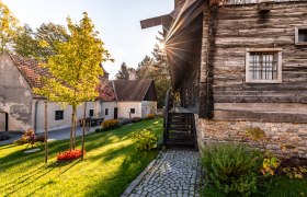 Traditionelle Geb&auml;ude und Gr&uuml;nanlage im Museumsdorf Krumbach bei Sonnenuntergang.