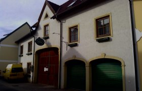 Außenansicht eines Gebäudes mit gelbem Van und grünen Garagentoren.