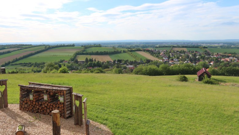 Aussicht vom Balkon Tullnerfeld auf grüne Felder und ein Dorf.