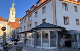 Außenansicht eines Restaurants mit der Aufschrift 'Cult Italia' und einem Kirchturm im Hintergrund.