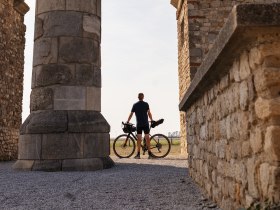 Ein Radfahrer genie&szlig;t die majest&auml;tische Kulisse des Heidentors, w&auml;hrend die warmen Sonnenstrahlen die alten Steine umspielen. Die sanfte Brise und die malerische Landschaft laden dazu ein, die Sch&ouml;nheit der Natur in vollen Z&uuml;gen zu erleben.