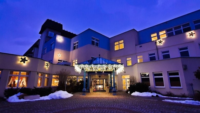 Gesundheitsresort Königsberg, © Gesundheitsresort KÖNIGSBERG, Bad Schönau Beleuchtetes Gebäude bei Dämmerung mit weihnachtlicher Dekoration.