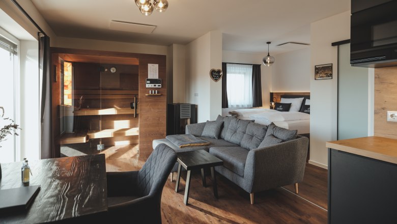 Chalet mit Sauna, © Chalaalets Innenansicht eines Chalets mit Sauna, Sofa und Bett.