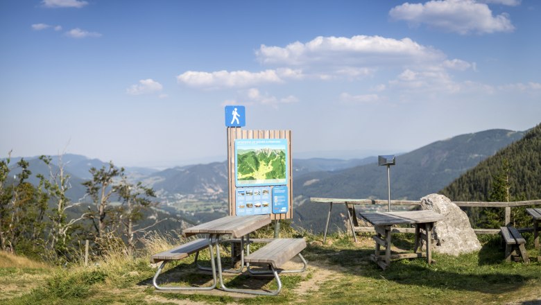 Picknicktische und Wanderschild mit Bergblick bei der Edelwei&szlig;h&uuml;tte am Schneeberg.