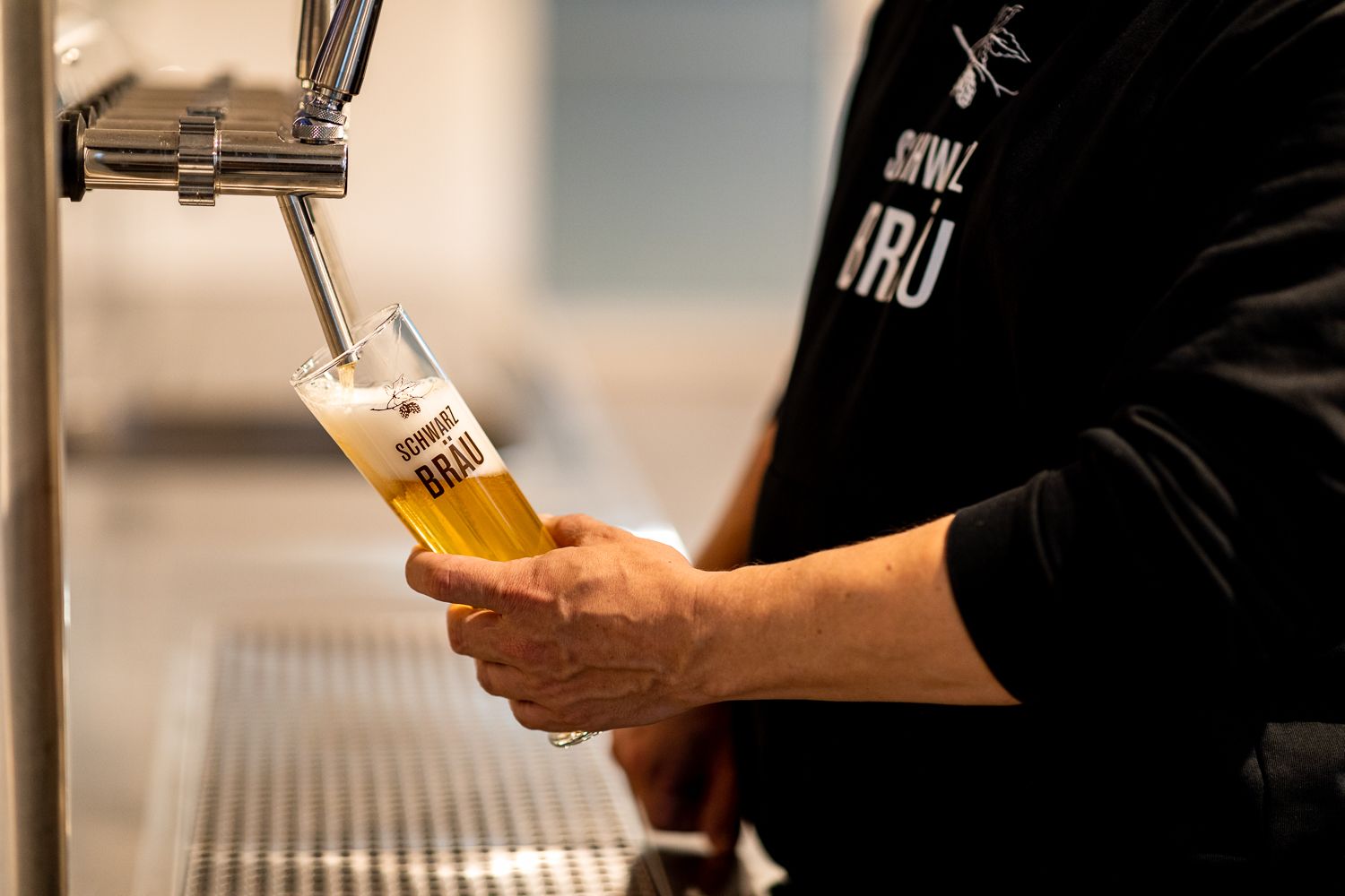 Eine Person zapft Bier in ein Glas mit der Aufschrift "Schwarzbräu".