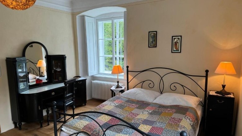 Gem&uuml;tliches G&auml;stezimmer mit Doppelbett, antikem Schminktisch und warmem Licht.