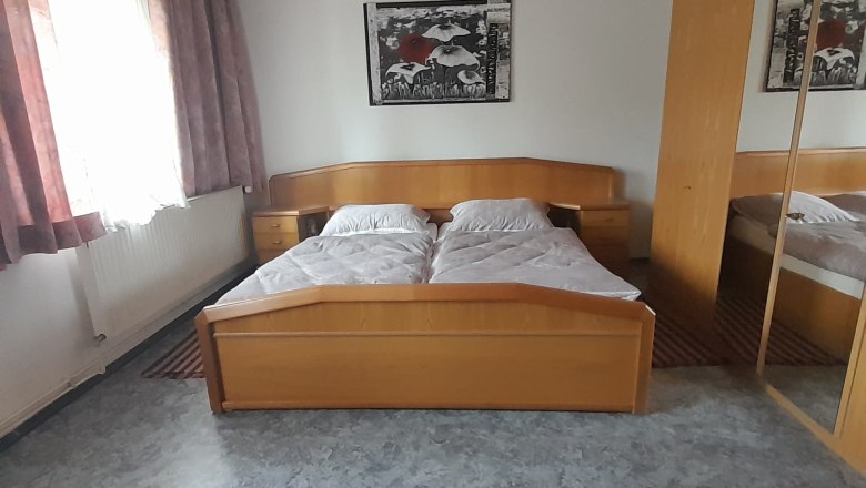 Schlafzimmer mit Doppelbett, Holzmöbeln und Spiegel.