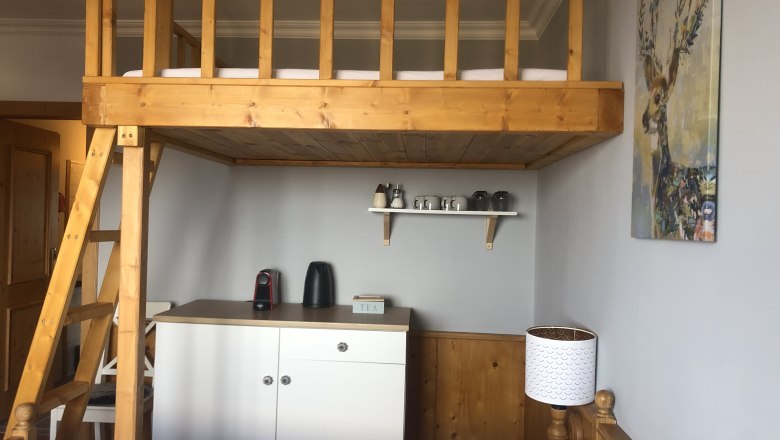 Zimmer mit Hochbett, Teestation und Hirschbild an der Wand.