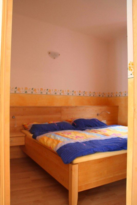 Schlafzimmer mit Holzbett und bunter Bettwäsche.