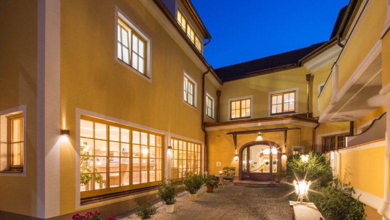 Innenhof des Hotel Zum Schwarzen Bären mit beleuchteten Fenstern und Pflanzen bei Nacht.