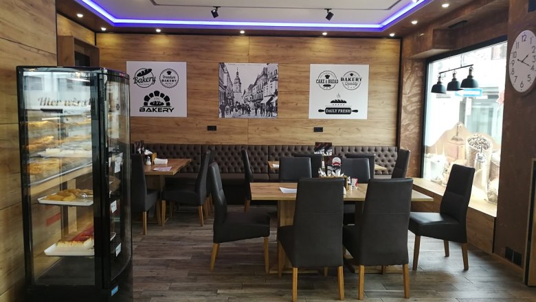 Innenansicht einer modernen B&auml;ckerei mit Holzw&auml;nden, Tischen und St&uuml;hlen.