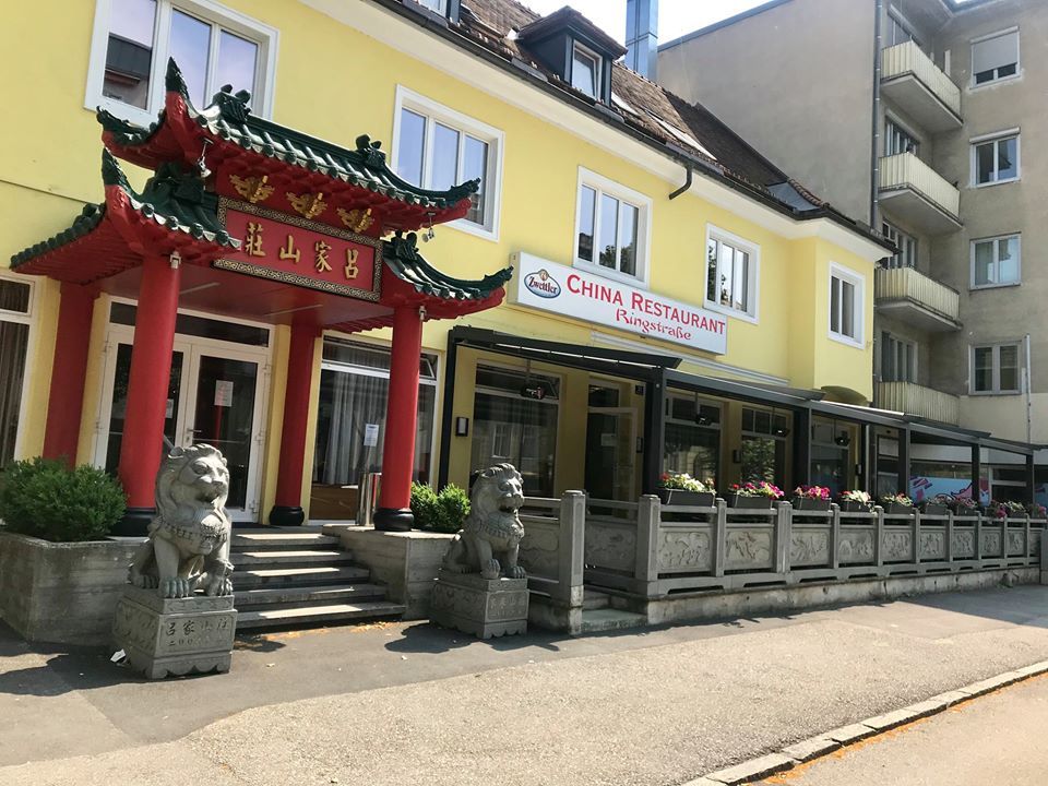 Außenansicht eines chinesischen Restaurants mit traditionellem Tor und Löwenstatuen.