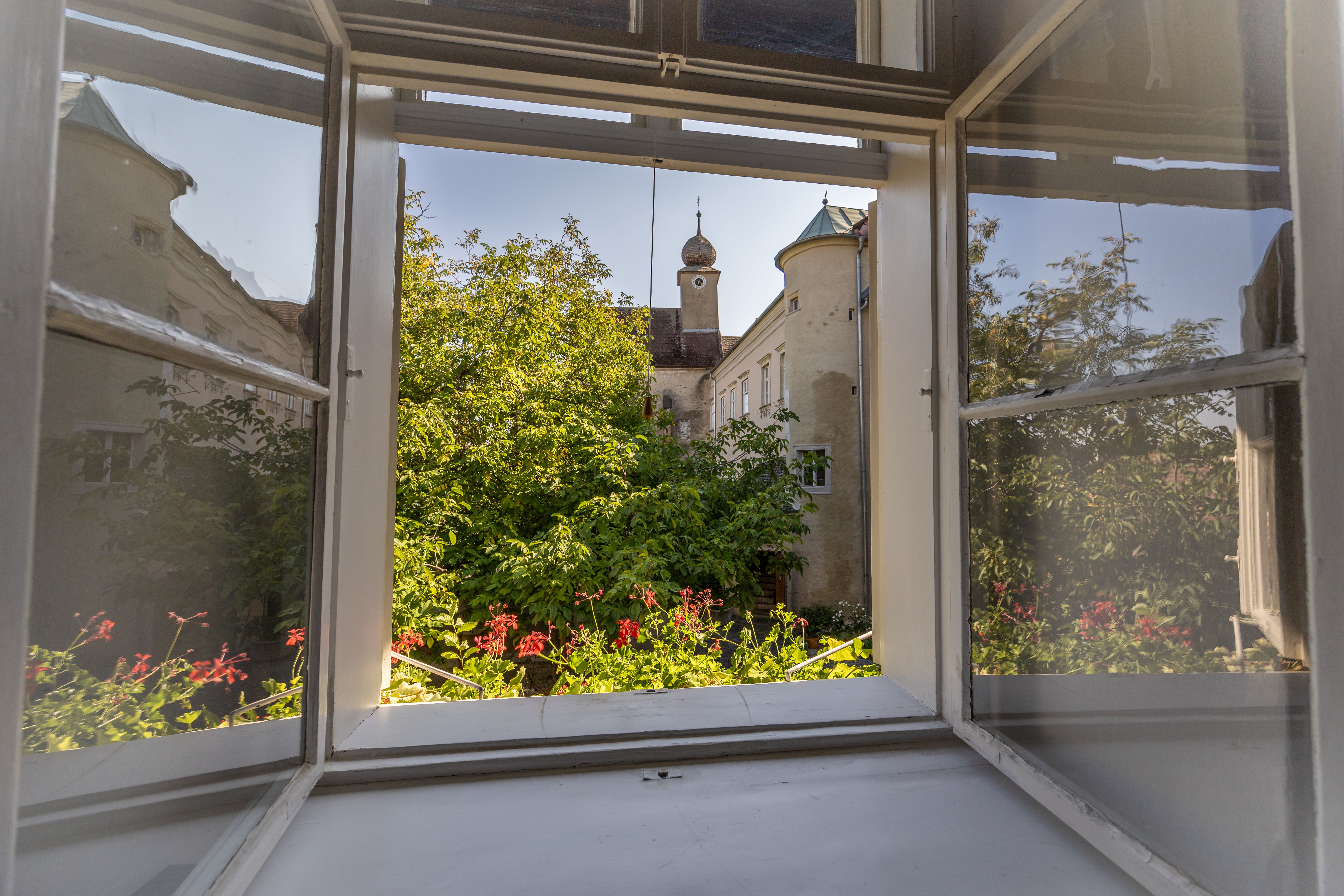 Schlafzimmer mit Gewölbedecke, Holzboden, Bett, Sessel, Kommode und Fellteppich.