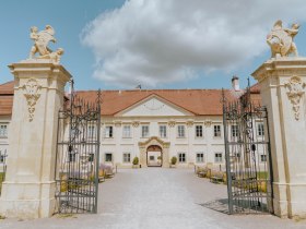 Eingangstor und Fassade von Schloss Marchegg unter blauem Himmel.