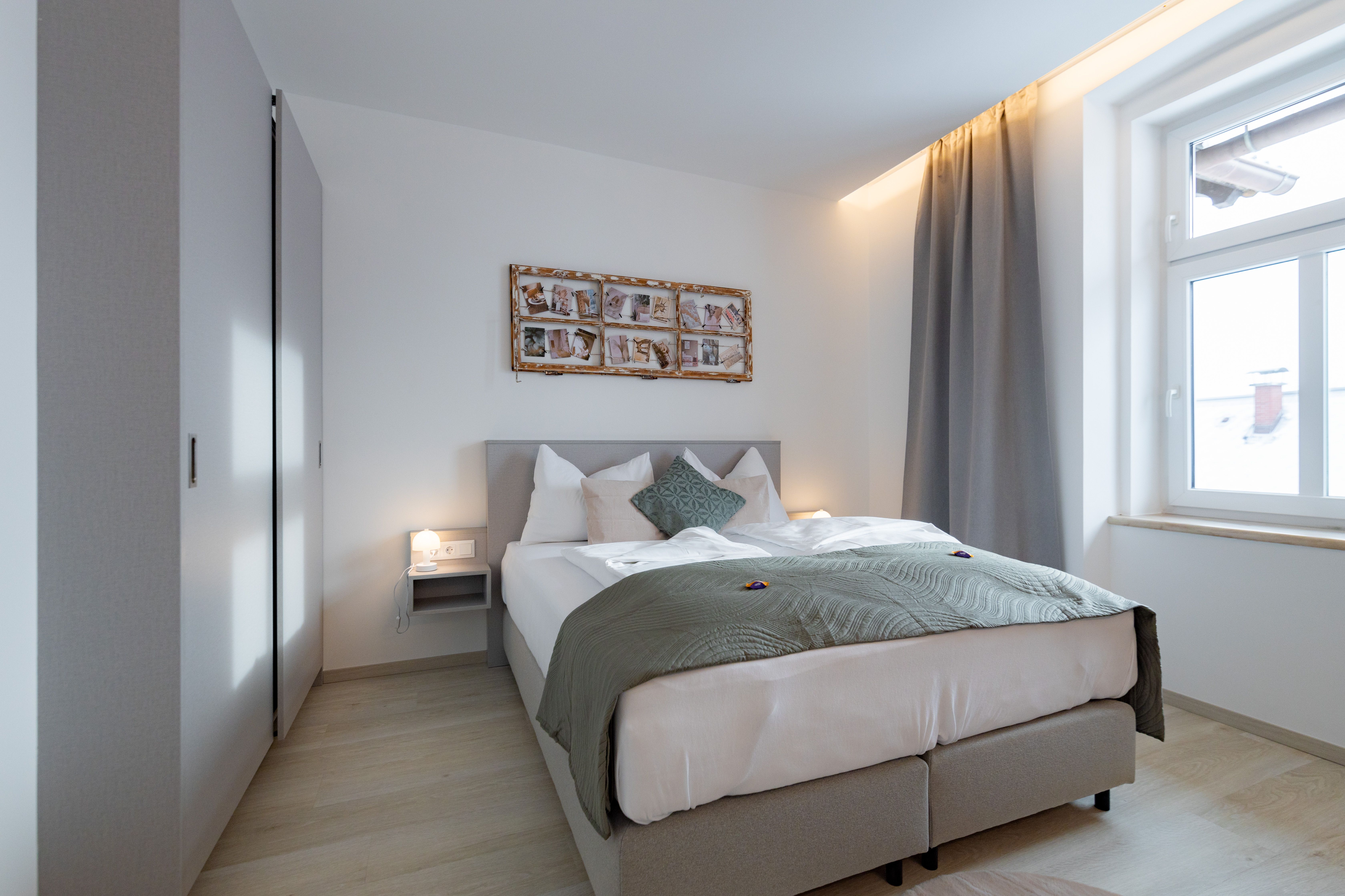 Modernes Schlafzimmer mit Doppelbett, grauen Vorhängen und Wanddekoration.