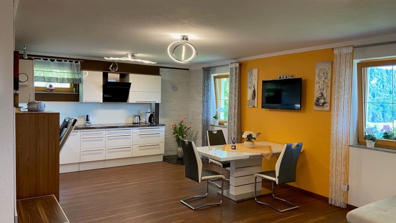 Moderne Wohnk&uuml;che mit Esstisch, St&uuml;hlen und Einbauk&uuml;che.