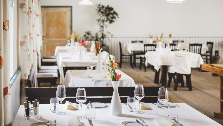 Elegantes Restaurant mit wei&szlig; gedeckten Tischen und Blumenvasen.