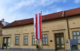 Au&szlig;enansicht des Museums Neunkirchen mit &ouml;sterreichischer Flagge und Informationsschild.