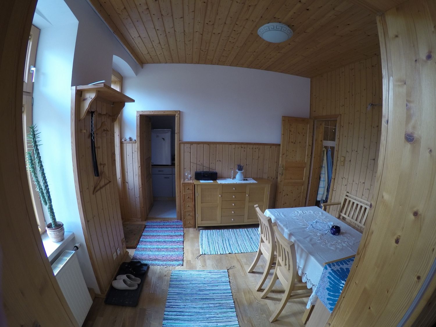 Esszimmer in einer Ferienwohnung mit Holzwänden, Esstisch, Stühlen und Teppichen.