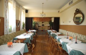 Ein traditionelles Gasthaus mit Holzboden, gedeckten Tischen und einem Kronleuchter.