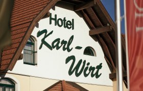 Fassade des Hotels Karl-Wirt mit rotem Dach und gr&uuml;nen Fensterl&auml;den.