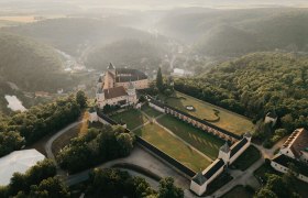 Luftaufnahme der Rosenburg inmitten gr&uuml;ner W&auml;lder und H&uuml;gel.