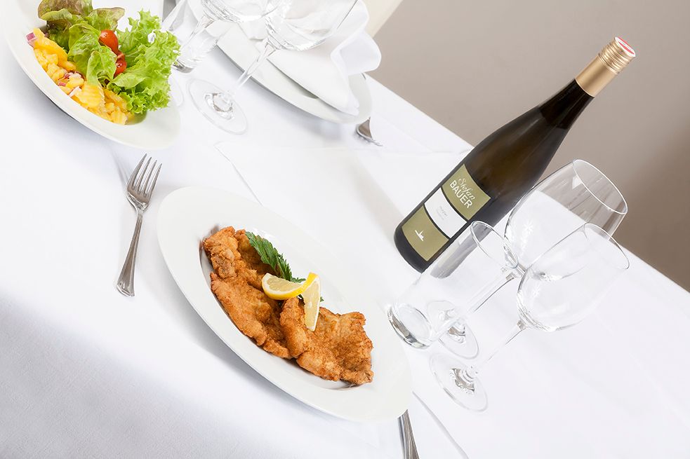Gedeckter Tisch mit Schnitzel, Salat und Weinflasche.