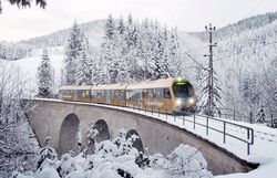 Garnitur der Mariazellerbahn fährt durch eine verschneite Landschaft